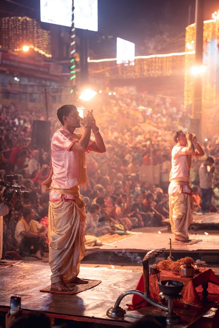 A vibrant Ganga Aarti ceremony with performers on stage amid a large crowd, showcasing Indian culture.