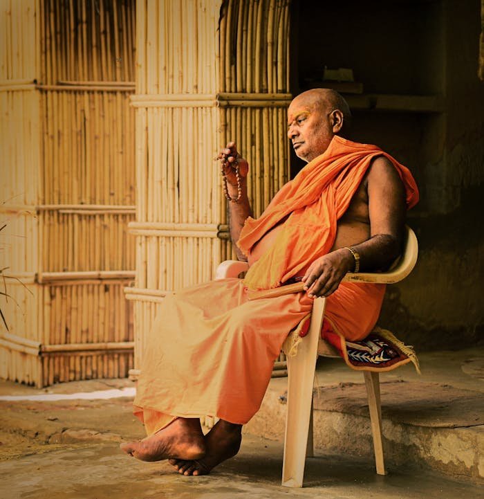A monk in traditional attire meditates peacefully in Mahaban Bangar, India.