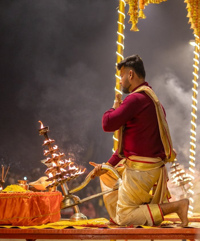 Priest performing Ganga Aarti ceremony on the ghats of Varanasi at night.